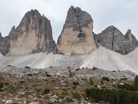       Close-up of the iconic three sheer rock towers of Tre Cime di Lavaredo rising from scree slopes.
  
