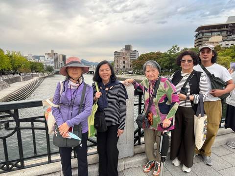       Group stands on bridge overlooking Hiroshima’s Peace Memorial Park and Atomic Dome.
  