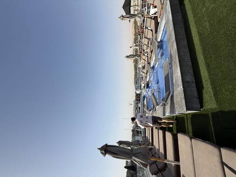       Rooftop pool deck on a Nile cruise ship with sun-loungers, umbrellas and a passenger walking alongside.
  