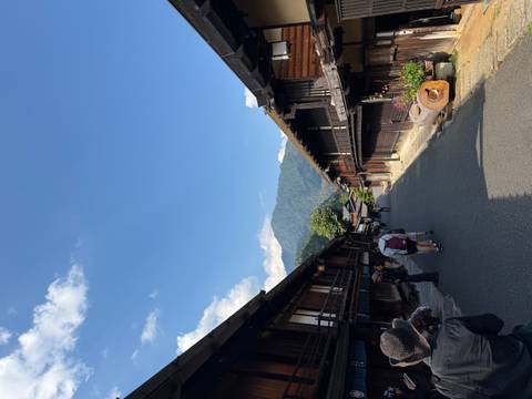       Traditional wooden houses line a quiet mountain village street under a clear blue sky.
  