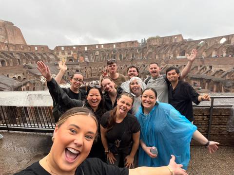       A cheerful tour group poses for a selfie inside Rome’s Colosseum on a rainy day.
  