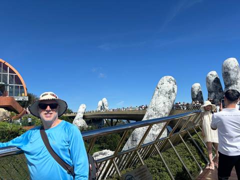       Visitors standing near Vietnam’s famous Golden Bridge with giant stone hands under a bright blue sky
  