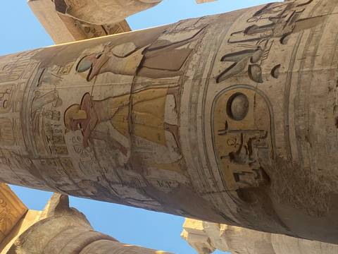      Close-up of richly colored hieroglyphic reliefs depicting pharaohs and deities on a massive temple column.
  