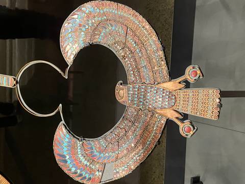       Exquisitely crafted ancient Egyptian pectoral jewelry in the form of a falcon displayed in a museum case.
  