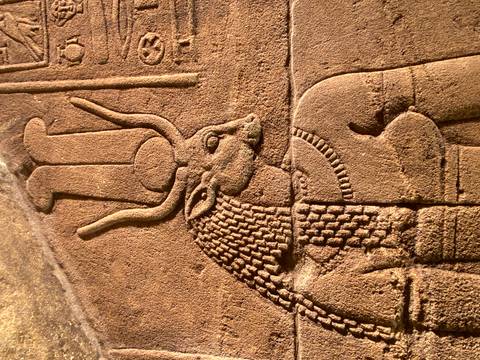       Close-up of an ancient Egyptian relief carving depicting a goddess with elaborate headdress.
  