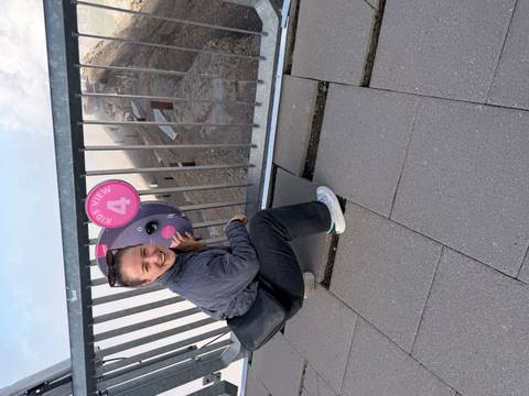       Traveller crouches by a railing above clouds holding a playful 'Kids View' sign.
  