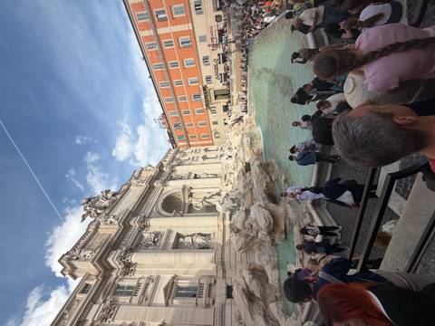       Crowds gather at Rome's Trevi Fountain with ornate baroque sculptures and turquoise water.
  