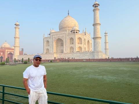       A traveler stands on the grassy forecourt with the Taj Mahal rising majestically behind him.
  