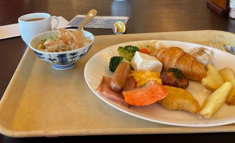       Cafeteria breakfast tray with assorted western and Japanese dishes beside a cup of coffee.
  