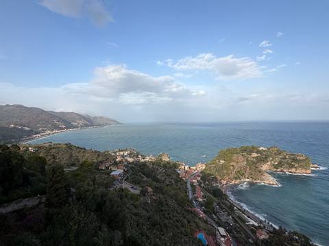       Panoramic coastal view of Sicilian hillside towns and expansive blue Mediterranean.
  