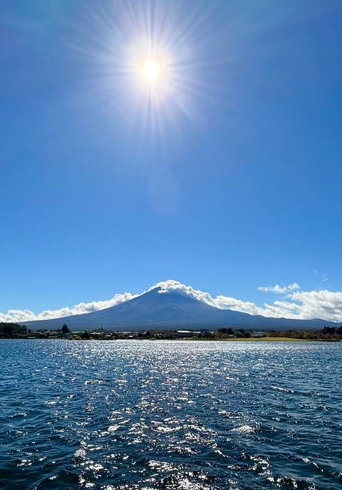       Snow-capped Mount Fuji rising above a clear blue sky and low clouds.
  