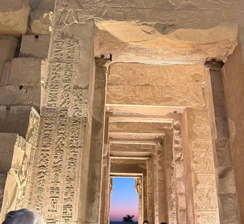       Detail of illuminated hieroglyph-covered pillars and doorways inside ancient Egyptian temple.
  