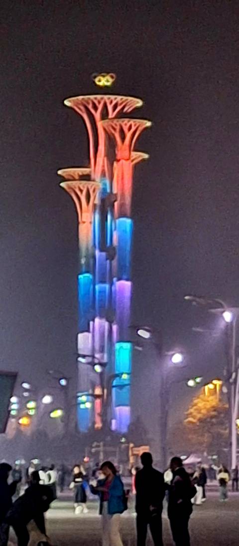      Nighttime close-up of a tall illuminated tower glowing in blue, purple and orange tones.
  