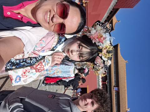       Travellers with a woman in ornate traditional dress inside the Forbidden City courtyard on a sunny day.
  