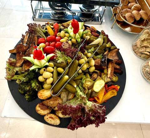       Colorful platter of grilled vegetables, olives and pickles arranged for sharing.
  