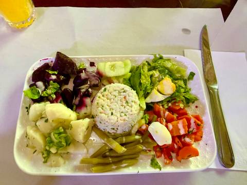       Tray meal of mixed Moroccan salads, rice, eggs and vegetables with cutlery on the side.
  