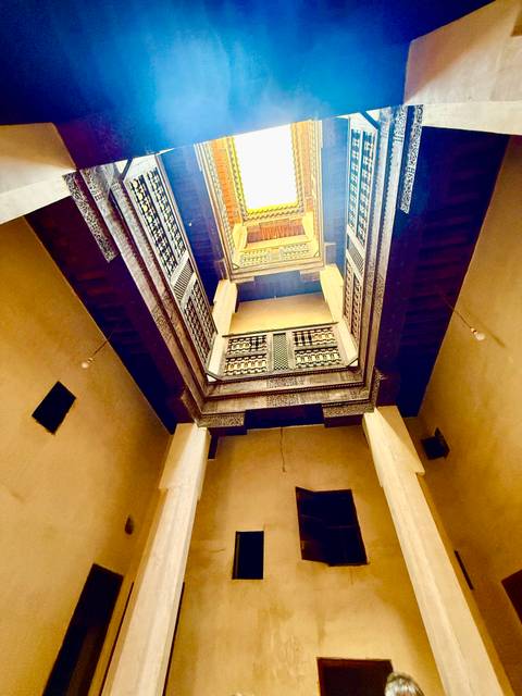       Looking up an ornate interior courtyard with carved balconies and warm light streaming from above.
  
