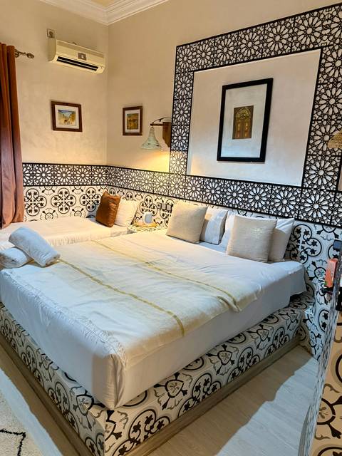       Stylish riad bedroom with patterned tile wall, crisp linens and warm ambient lighting.
  
