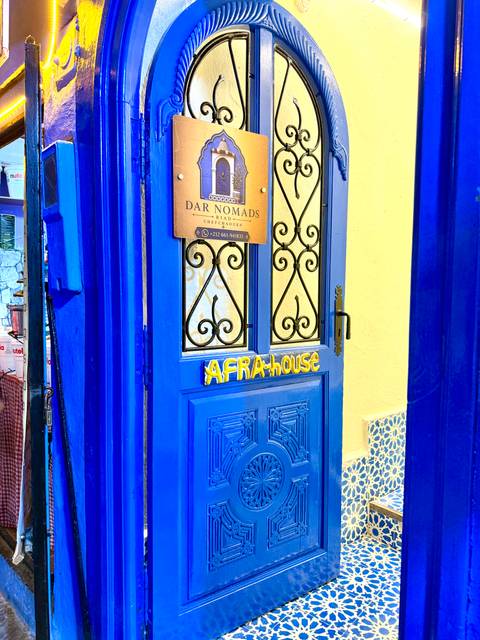       Bright blue door signed 'AFRAHOUSE' with wrought-iron window grills in Chefchaouen.
  