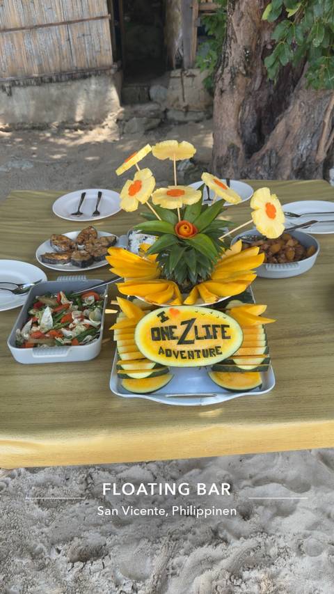       Colorful tropical fruit platter featuring a carved melon reading 'I ❤️ One Life Adventure' surrounded by sliced mango and salad dishes.
  