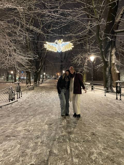 People walking on a snowy path under lit decorations.