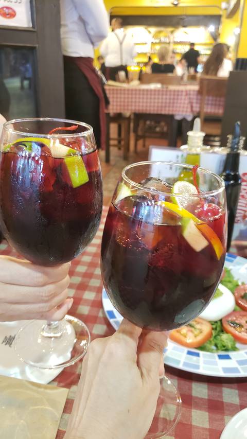 Two glasses of sangria held by people in a restaurant setting.
