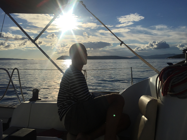Person sitting on a boat with a scenic sea view.