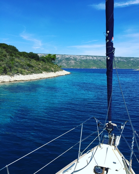 Sailboat close to a scenic coastline.