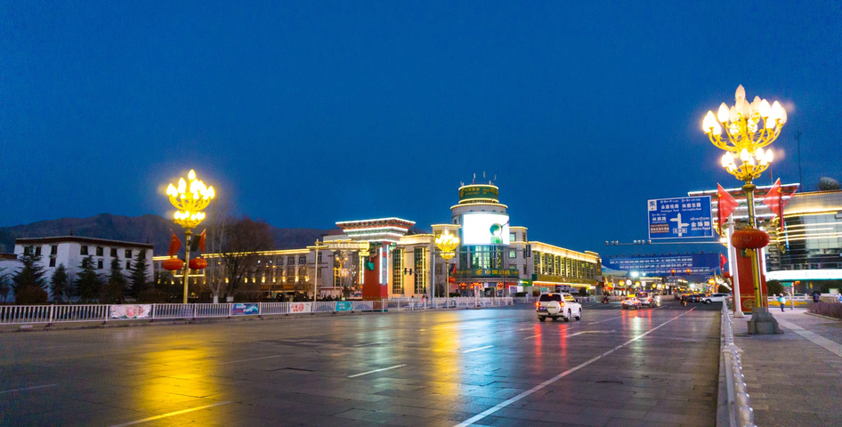 City street at night with brightly lit buildings and streetlights.