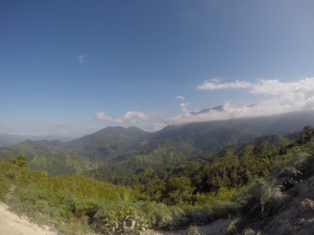 A scenic view of lush green mountains under a clear blue sky.