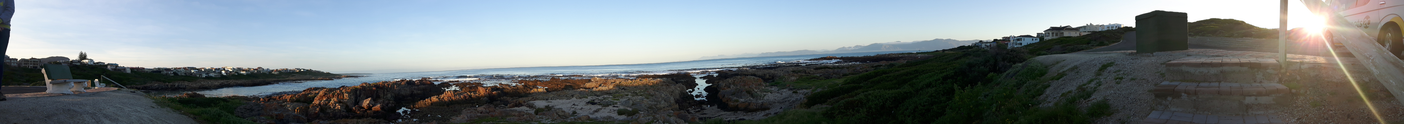 Rocky shoreline with ocean and sky view at sunset.