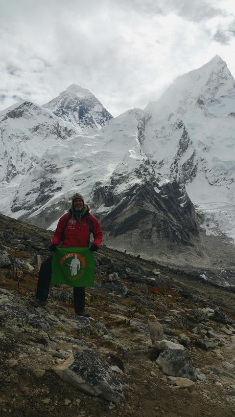       Person holding a flag with snowy mountains in the background.
  