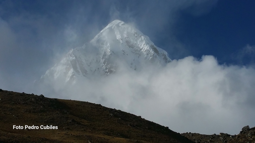       Mountain peak emerging through clouds with watermark text.
  