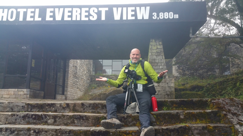       Man sitting on steps in front of Hotel Everest View.
  