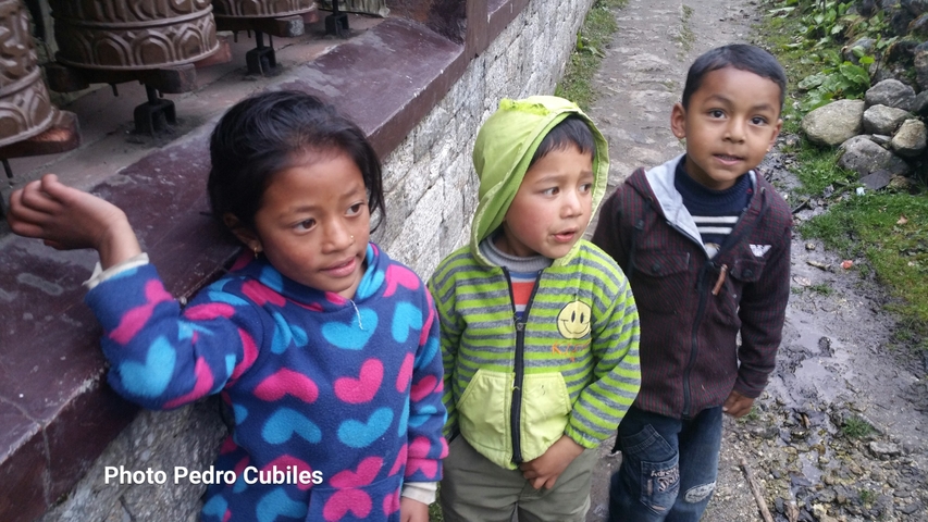       Children posing next to prayer wheels.
  