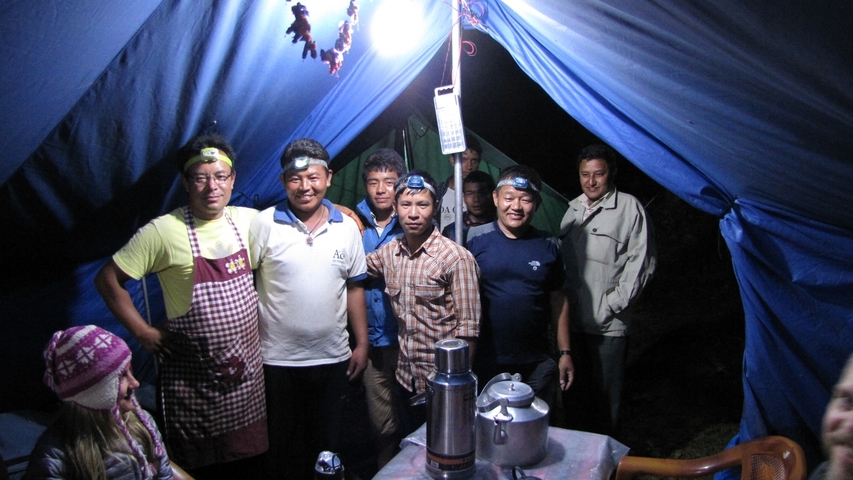       Group of people inside a tent around a table.
  