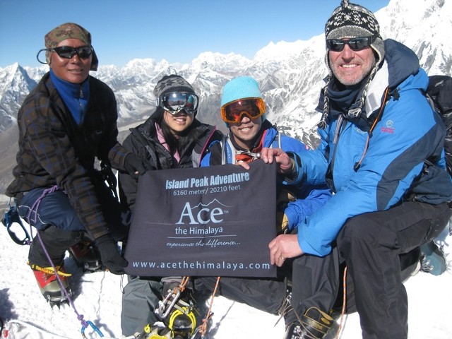       Group on a snowy peak holding a banner.
  