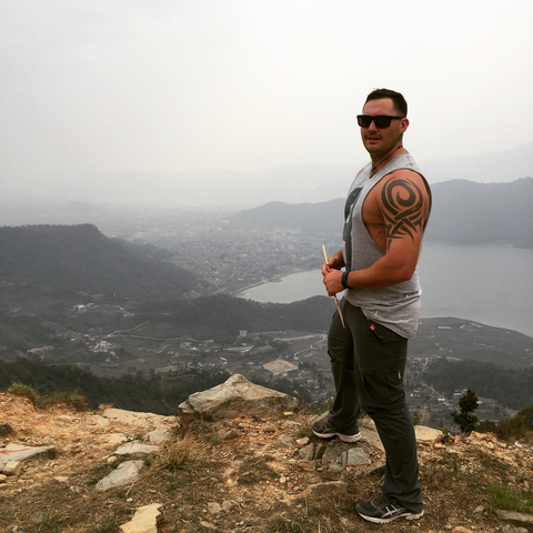 Person standing on a hill overlooking a lake and city.