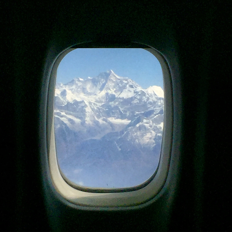 View of snow-capped mountains through an airplane window.