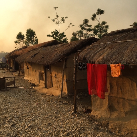 Traditional straw huts with colorful clothes drying.