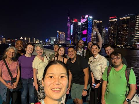       Upside-down view of a group of people smiling with Shanghai's skyline in the background.
  