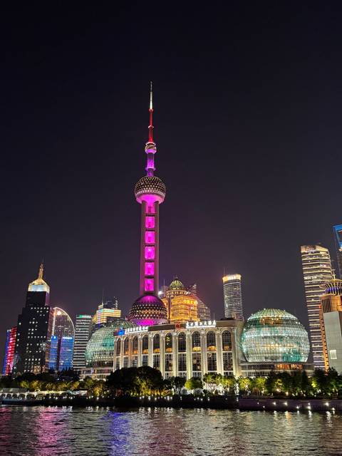 The Oriental Pearl Tower illuminated with pink lights at night.