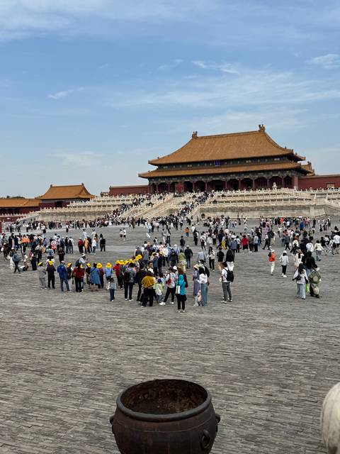 Tourists walking through the Forbidden City in Beijing, a historical complex with ancient architecture.