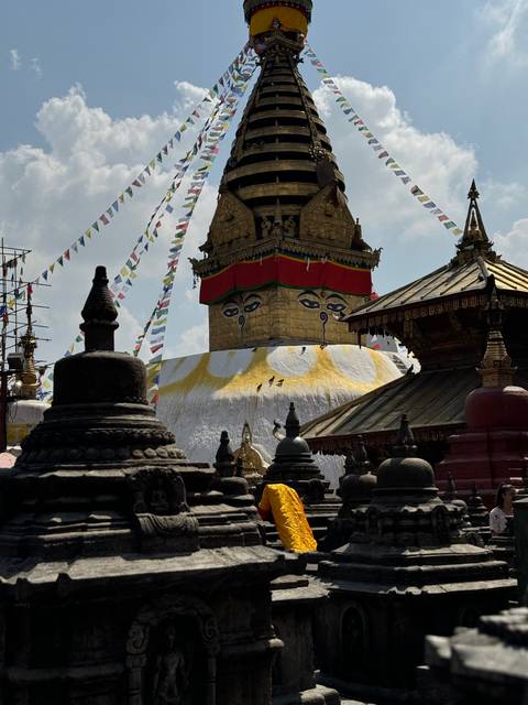 A Buddhist stupa with prayer flags against a blue sky