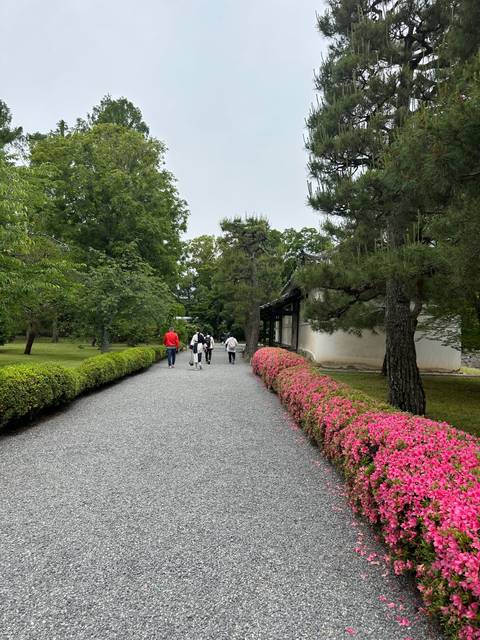 People walking on a path with trees and flowers lining the sides.