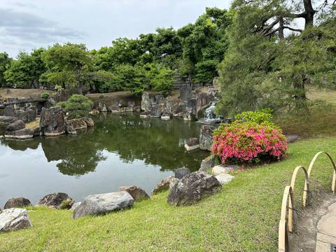       Garden with pond, rocks, and greenery.
  