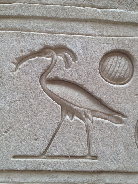 Stone carving of a bird and symbols.
