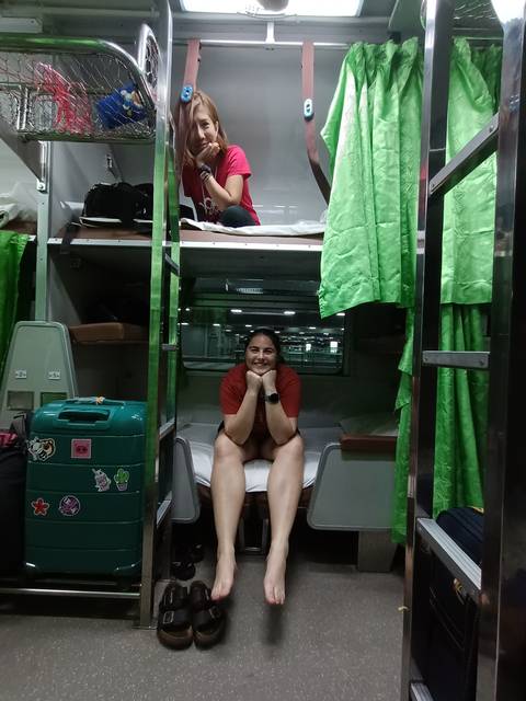      People inside a bunk bed train compartment.
  