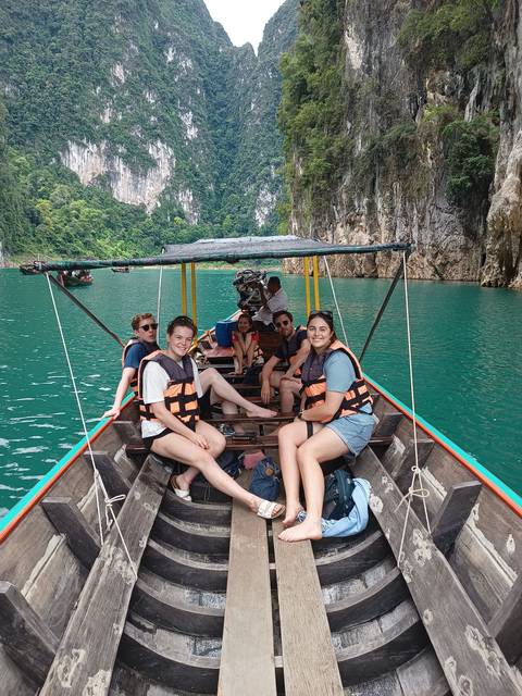 Group in a boat tour on a green lake with steep cliffs.