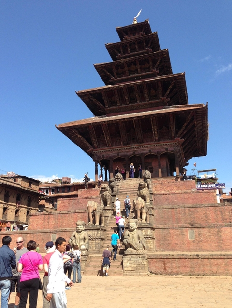Pagoda style temple with people and statues at the entrance.
